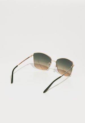 Hatszögletű napszemüveg, gradient lencsékkel, aranyszínű fém kerettel és sötétzöld, textúrált designt képviselő szárakkal. Átlátszó orrpárnák included.