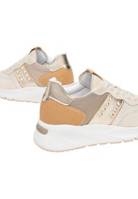 Sneaker beige con accenti metallici, tessuto texture, dettagli con borchie e suola bianca. Presentano una combinazione di materiali in rete e suede.