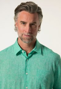 Světle zelená, texturovaná košile na knoflíky s kapsou a špičatým límcem, vybavená jemným tkaným vzorem a bílými knoflíky.