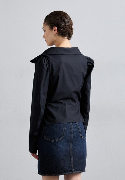 Μαύρο, εφαρμοστό σακάκι με φουσκωτά μανίκια και μεγάλο γιακά, συνδυασμένο με μια σκούρα τζιν φούστα; λείος υφασμάτινος τύπος, δομημένος σχεδιασμός.