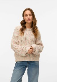 Maglione chunky a maglia grossa rosa chiaro con motivi a treccia e colori screziati. Collo e polsini a costine, con una vestibilità morbida. Indossato con jeans blu.