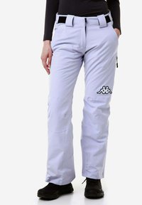 Pantaloni da sci di colore viola chiaro con cintura nera, tasche cargo e un logo bianco sulla parte inferiore della gamba. Il tessuto sembra liscio e resistente all'acqua.