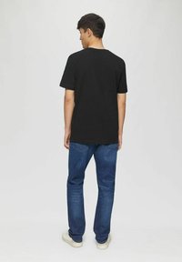 Black cotton t-shirt with a regular fit, short sleeves, and crew neck, paired with blue denim jeans and white sneakers.