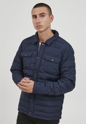 Navy-blau gesteppte Jacke mit Druckknopfverschluss, zwei Brusttaschen und Kragen, die eine glatte Textur und eine gerade Passform bietet.