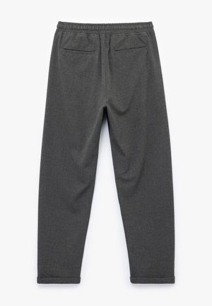 Pantalones grises texturizados con una cintura elástica, dos bolsillos traseros y piernas estrechas con un sutil patrón de cuadros.