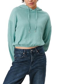 Felpa corta verde menta con finitura testurizzata, coulisse e maniche larghe, abbinata a jeans di denim blu scuro.