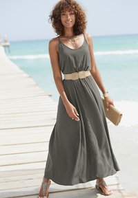 Elegantes graues Maxikleid mit Spaghettiträgern, taillierter Taille und einem gewebten beigefarbenen Gürtel; kombiniert mit flachen Sandalen und einer Strohtasche.