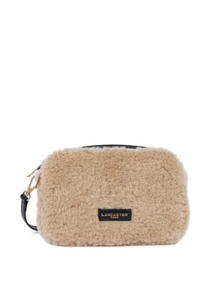 Beige faux fur crossbody bag with black leather accents and gold hardware. Features a zip closure and embossed brand label.