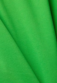 Tissu vert avec une texture lisse et des plis subtils, montrant des détails fins de tricotage et une apparence de matériau doux.