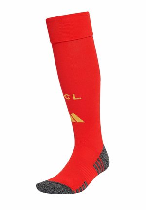 Chaussette de sport rouge montante jusqu'au genou avec orteil et talon renforcés gris, avec logo et lettres jaunes sur la zone du mollet.
