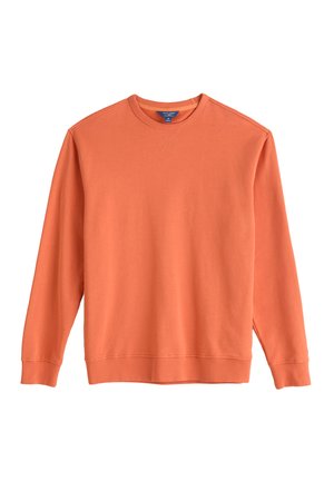 Oranžna majica s kapuco, narejena iz mehke flis tkanine, z ribanim manšetami in robom ter z stitch detajlom na izrezu.