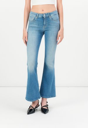 Light blue flared jeans made of denim, featuring a high waist and a subtle fade, paired with black patent leather shoes.