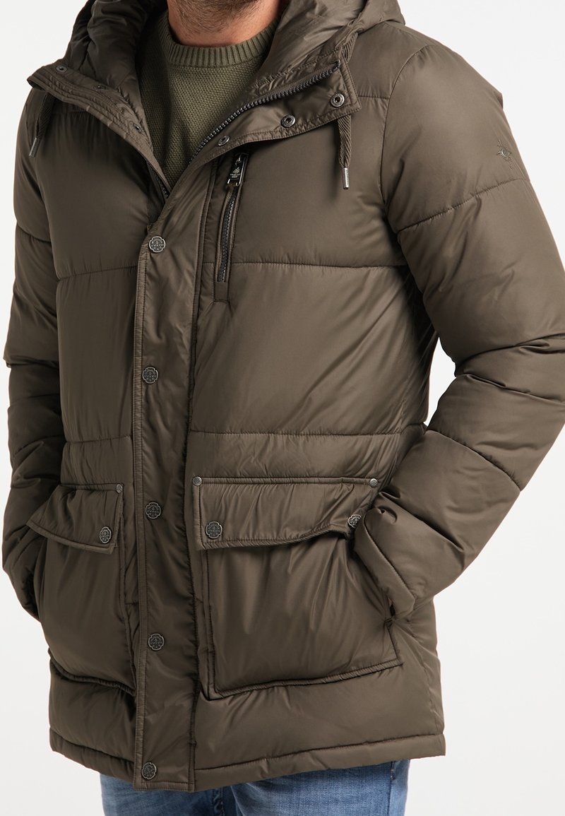 Veste matelassée vert olive avec capuche, dotée de boutons-pression, deux poches avant et une poche poitrine zippée. Texture lisse et design matelassé.
