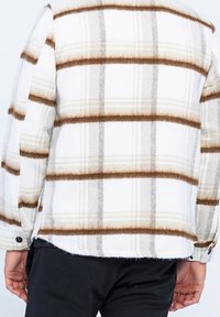 Ull-flanellskjorta i vitt med brun och tan-rutig mönstring, med spetsig krage och knappmanchetter. Texturerat tyg och rak passform.