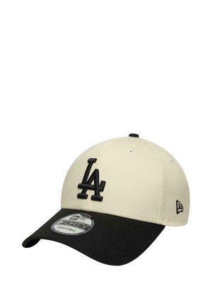 Baseball cap with a cream crown, black brim, and raised black "LA" logo on the front, featuring an adjustable design.