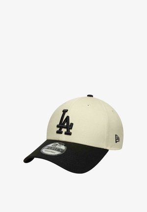 Gorra de béisbol con corona crema, visera negra y logotipo en relieve "LA" negro en la parte frontal, con diseño ajustable.