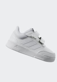 Witte sneaker met een gestructureerde bovenkant, twee klittenbandsluitingen en drie strepen aan de zijkant. Lichtgewicht, duurzame zool met een geprofileerde loopvlak.