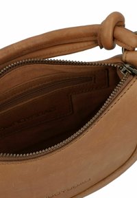 Tan leren handtas met een ritssluiting, voorzien van een binnenzak en een gladde textuur. De handvatten hebben een geknoopt ontwerp voor extra grip.