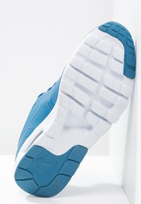 Sneaker Nike Air blu angolato per mostrare la suola testurizzata bianca e blu su sfondo bianco.