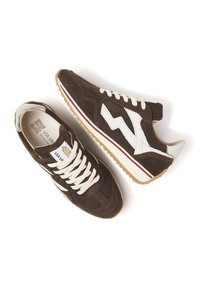 Baskets en daim marron avec des accents blancs, design en zigzag embossé, lacets blancs et semelle en gomme. Présente une rayure bordeaux le long de la semelle.