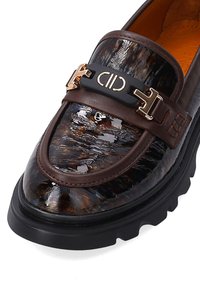 Braune Lederloafer mit glänzendem Schildpatt-Obermaterial, ausgestattet mit einem schwarzen Riemen und goldfarbenen Hardware-Akzenten sowie einer dicken schwarzen Sohle.