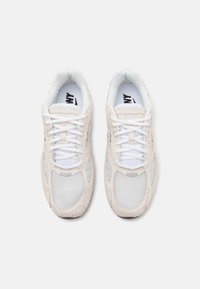 Beige ruskind og mesh sneakers med hvide snørebånd, der har en polstret krave, mesh sidepaneler og logo på indersålen. Gummiydersål.