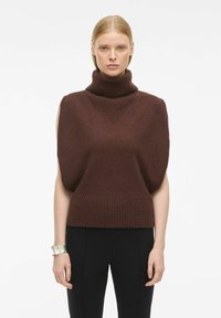 Tumša brūna īsām piedurknēm turtlenecka džemperis, ar ribotiem malām un tekstūrētām plecu detaļām. Pievienots sudraba rokassprādze.