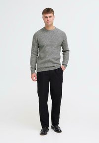 Hall tohveliga halli kudumine särk ümarate kaelustega, koos mustade pihtidega pükste ja mustade kingadega. Lihtne disain, sile tekstuur.