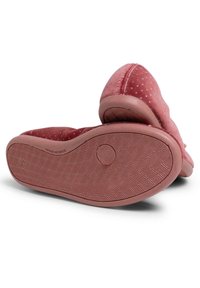 Pantofole di tessuto rosa con una superficie testurizzata e piccoli accenti metallici. Le suole in gomma presentano un motivo a spina di pesce per migliorare la trazione.