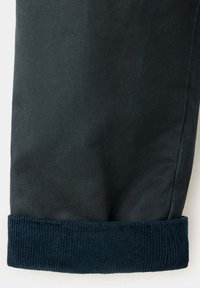 Jambe de pantalon vert foncé avec un revers plié en velours côtelé bleu marine.
