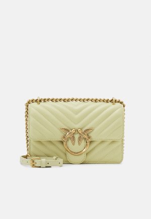 Bolso bandolera de cuero verde claro acolchado, con cadena dorada como correa y cierre frontal en forma de pájaro dorado.