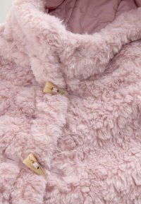 Faux fur pink jakke med en blød, tekstureret finish. Har en høj krave og en cremefarvet toggleknap til lukning.