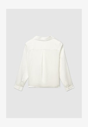 Blusa di raso bianco con balza posteriore, maniche lunghe e polsini con bottoni. Tessuto liscio con una vestibilità rilassata e design minimalista.