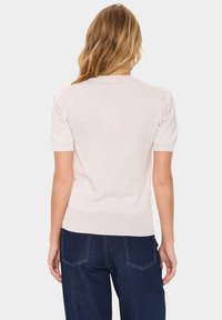 Světle růžový svetr s krátkými nabíranými rukávy, žebrovaným lemem a hladkou texturou, zobrazený zezadu s tmavě modrými džíny.