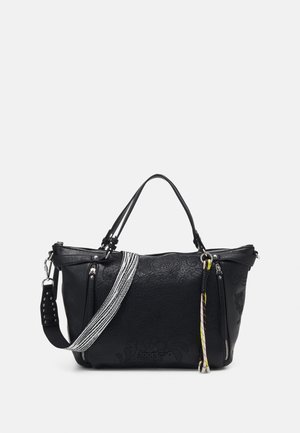 Sac à main en cuir texturé noir avec double poignée, une bandoulière rayée noir et blanc et un pompon tressé coloré sur la fermeture éclair.
