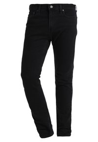 Czarne dżinsy z wąskim krojem. Posiadają zamek błyskawiczny, standardowy układ pięciu kieszeni oraz przeszycia po bokach.