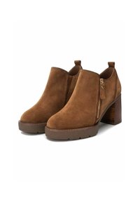 Stivali alla caviglia in suede marrone con tacco spesso, suole texturizzate e zip laterale. Presentano un'etichetta sul retro per una facile calzata.