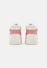 Mid-top sneakers med en pastellrosa suede-overdel og hvite syntetiske lærdetaljer. Inkluderer en borrelåsrem og teksturert gummisåle.