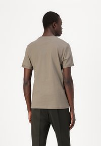 Kratkoročna khaki majica s kratkimi rokavi in krožnim izrezom, izdelana iz bombažnega blaga, z sproščenim krojem in minimalističnim dizajnom.