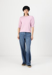 Light pink knitted sweater with short puff sleeves, paired with light blue flared jeans and black flat shoes. Model wears a black beret.