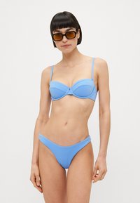 Lys blå bikini-sett som inkluderer en bh med undertråd og tynne stropper, kombinert med matchende lavtkuttet bunn og glatt tekstur.