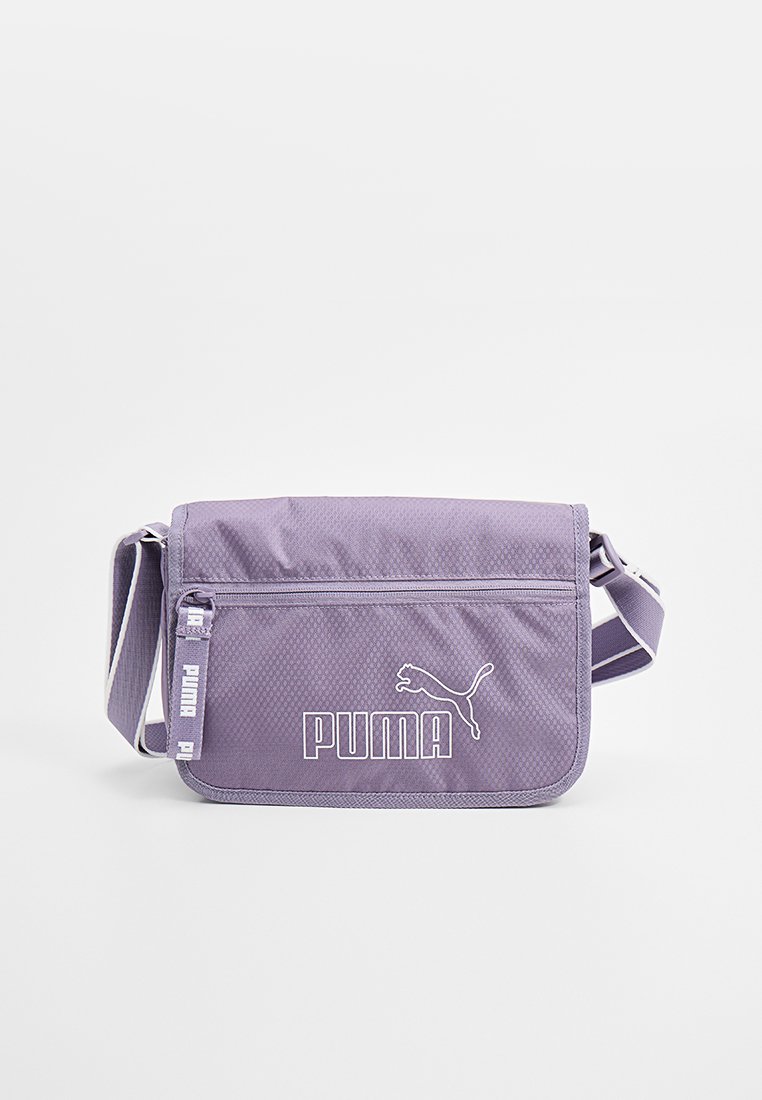 Bolso de hombro de tela morada con correa ajustable, que cuenta con un tapa frontal, cierre de cremallera y el logo y acentos blancos de Puma. Material texturizado.