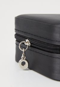 Black zippered case with a smooth texture, featuring a silver zipper pull and a round accent. Compact rectangular shape.