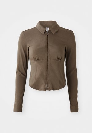 Brun zip-jakke med lange ermer, krage og rynkedetaljer ved brystet. Laget av et glatt, elastisk stoff.