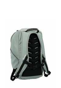 Mochila de tela gris con un respaldo estructurado y acolchado, correas ajustables y un asa en la parte superior. Presenta un diseño ventilado con acentos en negro.