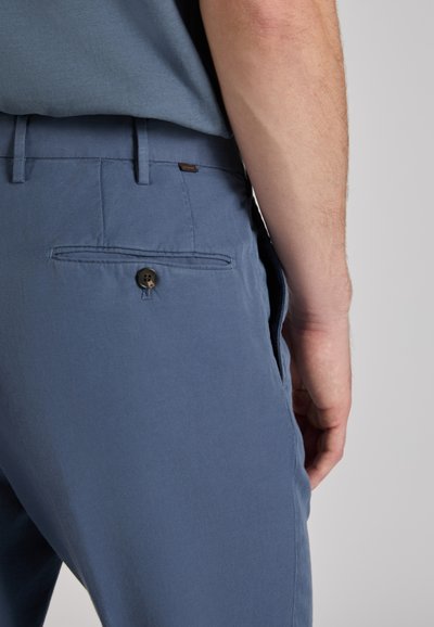 Light blue trousers with a smooth texture, featuring a single back pocket secured with a brown button and belt loops.
