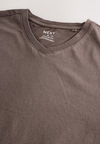 Braunes Baumwoll-T-Shirt in mittlerer Größe mit V-Ausschnitt und dem Aufdruck "NEXT M Regular Fit Made in Bangladesh" innen im Kragen.