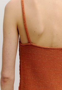 Gebreide tanktop in roestkleur met dunne bandjes, voorzien van een gestructureerd patroon en subtiele metallic draadaccenten doorheen.
