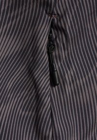 Strukturiertes Gewebe mit kontrastierenden dunklen und hellen Streifen, versehen mit einem schwarzen Reißverschluss mit Schlitten an einer Seitennaht zur Schließung.