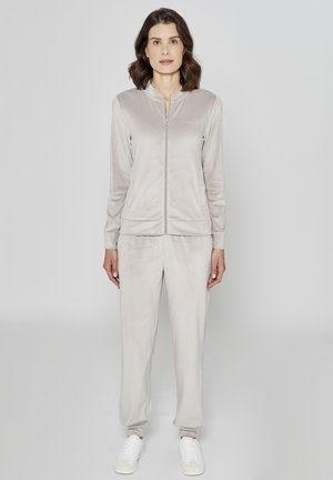Lys grå, myk velourdress med glidelåsjakke og bukser med elastisk midje. Har ribbede mansjetter og diskret merkevare.